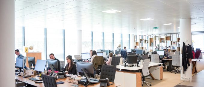 Modern open office layout with employees working in a noisy, distraction-filled environment.